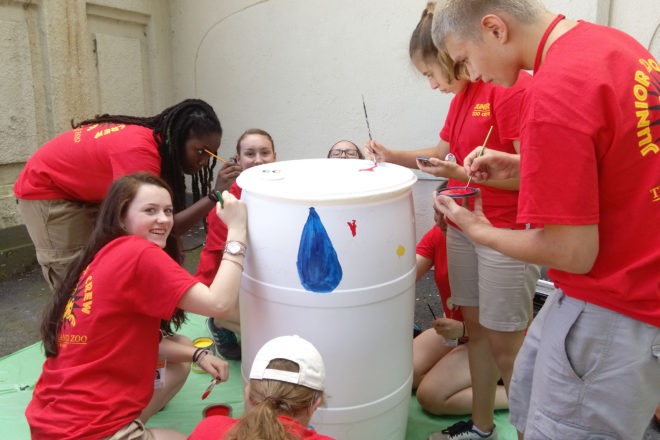 teen volunteers painting rain barrel