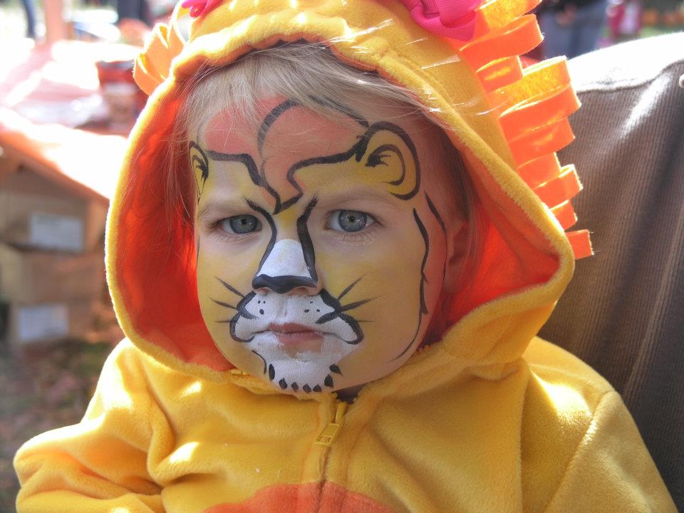 Child with face painted like a lion