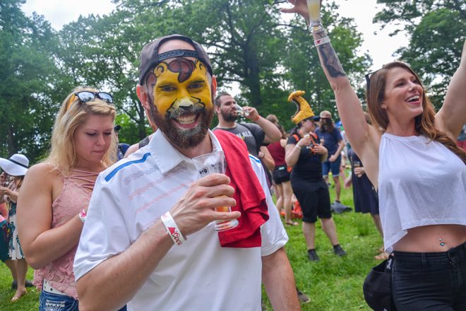 man with face paint holding beer glass